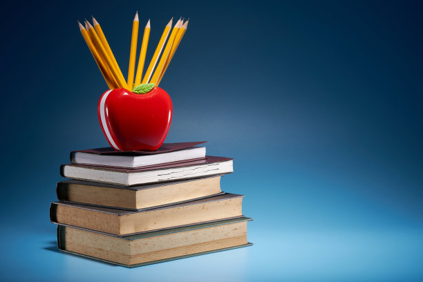 苹果形状的铅笔筒，蓝色的背景上有一摞书图片下载