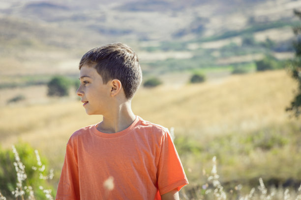一个11岁男孩站在田野里的侧面图片下载