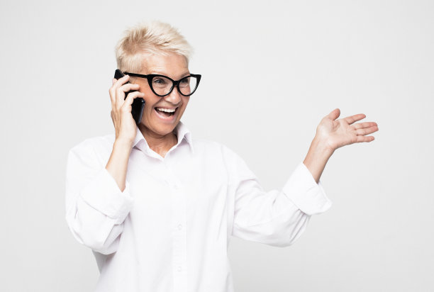 伟大的新闻。现代通信。快乐的高级妇女使用手机在灰色背景。图片下载
