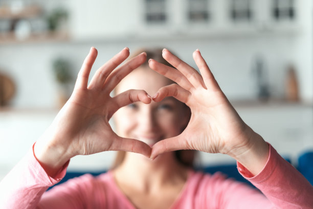 快乐的年轻女子做心形的手势图片下载