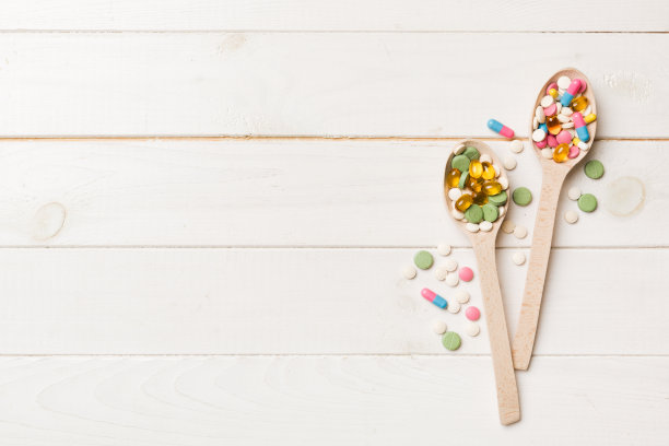 在彩色背景的木勺里装着维生素胶囊。药片作为健康的一餐。药品、药房、医药或医疗保健理念图片下载