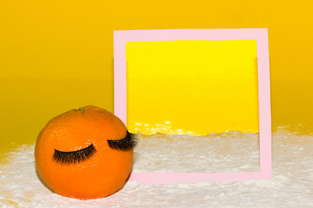 橙色的水果在一个粉红色的画框前，里面有复制空间，画框的背景和周围是一个海滩，有创造性的画日落，浪漫的夏天设计图片下载