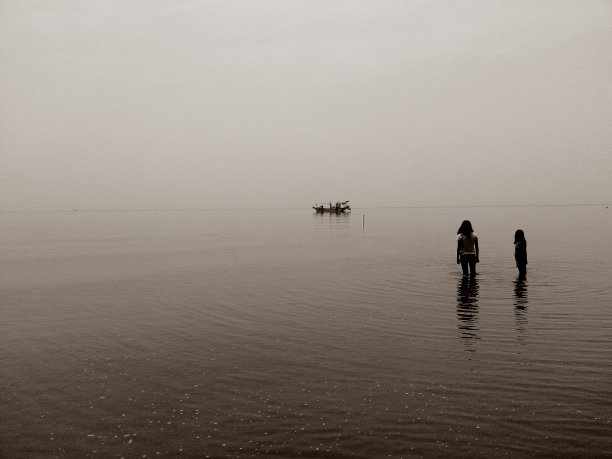 一艘船和两个女孩在平静的海边图片下载
