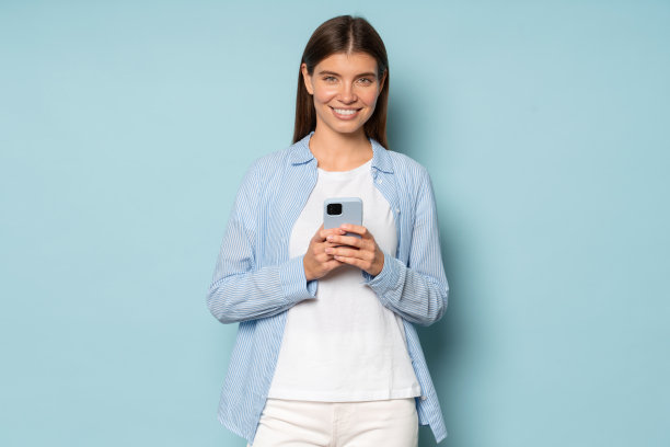 漂亮微笑的女孩寻找工作使用手机应用程序在蓝色背景图片下载