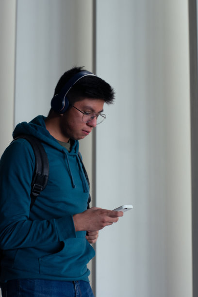 一名年轻人一边用手机打字，一边走下楼梯图片下载