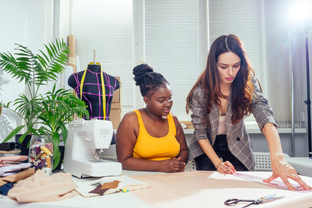 美丽的女裁缝长头发和非洲裔顾客。裁缝在缝纫车间时装屋为她创造了一个形象图片下载