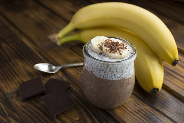 木制背景的玻璃罐里有奇亚籽和香蕉的巧克力布丁。特写镜头。图片下载