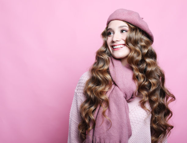 美丽的年轻女子与长波浪头发戴着粉红色贝雷帽和围巾图片下载