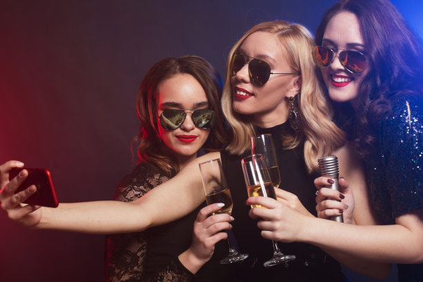 一群参加派对的女人一边吹着笛子，一边喝着气泡酒自拍。图片下载