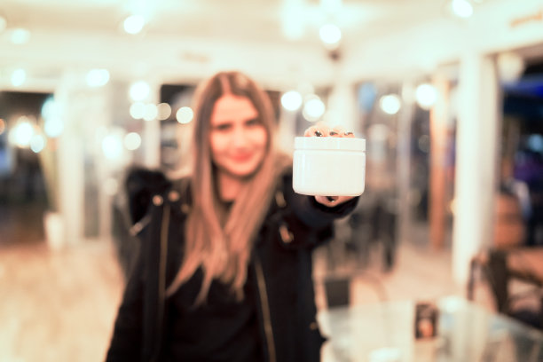 散焦美丽的女人持有霜或美丽的白色容器在她的手复制空间图片下载