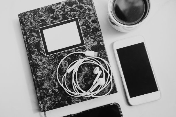 俯视图拍摄的白色电缆耳机在白色背景与智能手机，黑咖啡和笔记本图片下载