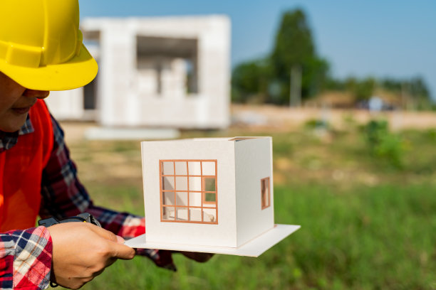 工程和建筑师妇女与房屋模型在建筑工地工作。图片下载