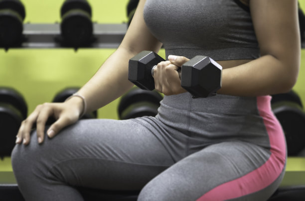 在对哑铃的选择性关注中，哑铃被女人握着，做运动，图片下载