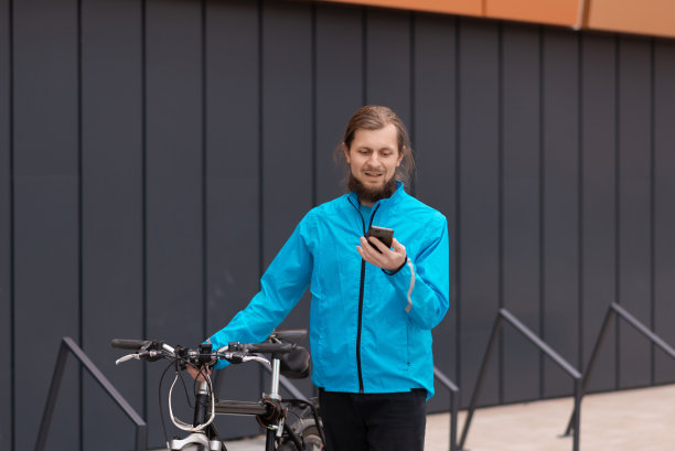 一个留着大胡子的年轻人在城市里推着自行车走路图片下载