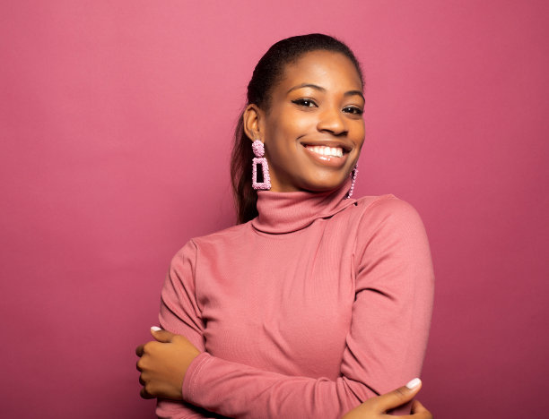 年轻美丽微笑的肖像黝黑皮肤的女人孤立在粉红色的背景。图片下载