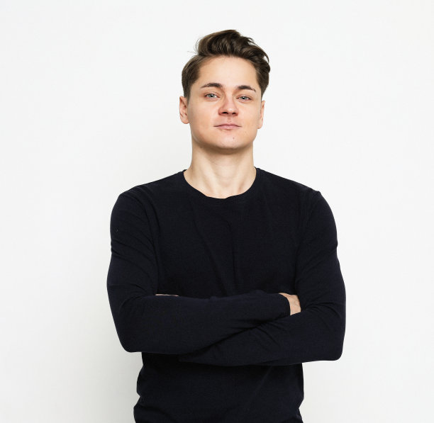 年轻英俊的男子穿着黑色毛衣交叉双手看着镜头图片下载