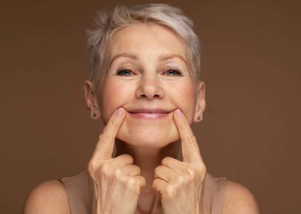 美丽的高级女性的肖像触摸她完美的皮肤，看着相机。图片下载
