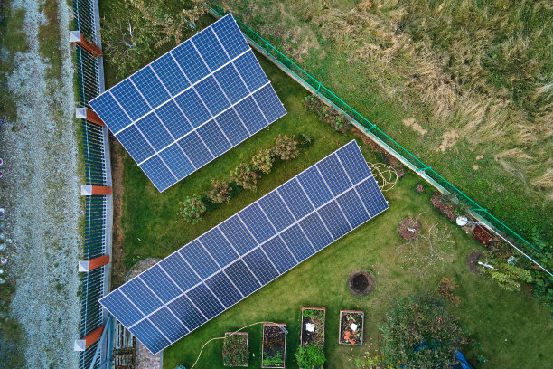 太阳能光伏板安装在后院地面的独立框架上，用于产生清洁的生态电能。自主住宅的概念图片下载