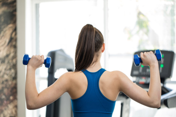 美丽的年轻女运动员在健身房举重。库存照片图片下载