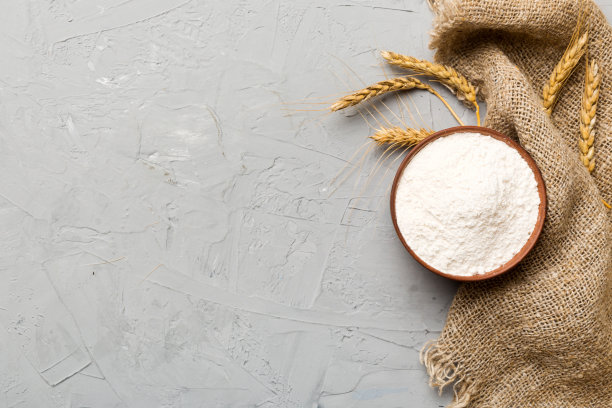 将小麦粉平铺于木碗中，彩色底色上点缀着小麦穗。世界小麦危机图片下载