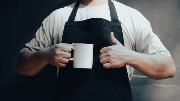 穿着围裙的男人一只手拿着咖啡杯，另一只手竖起大拇指。咖啡店横幅设计。图片下载