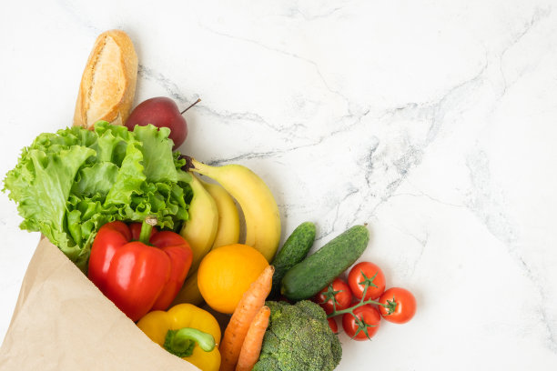棕色纸袋装满了新鲜的水果和蔬菜在白色大理石背景。购物配送服务理念。健康饮食理念。自由空间。平躺图片下载
