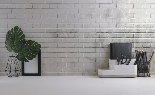 家庭办公室内部。室内植物，咖啡杯，书和笔筒在白色的桌子上。图片下载