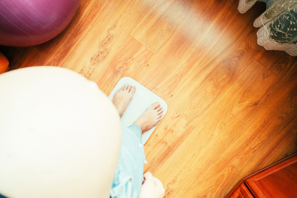 孕妇体重增加。幸福的孕妇站在体重秤上。怀孕的概念，母性，对婴儿的期望。图片下载