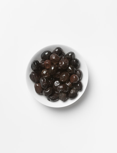 黑色橄榄在白色的碗里，在一个浅色的背景上，从上面看图片下载