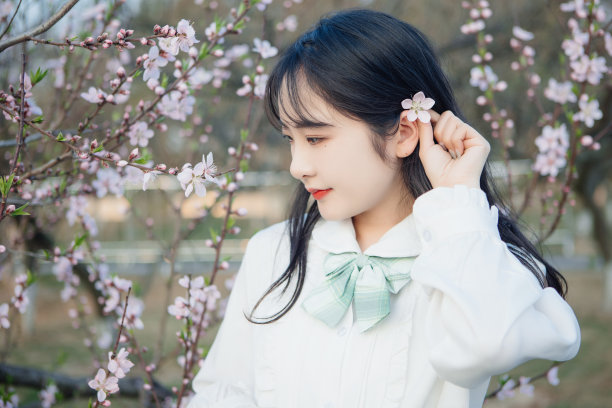 美丽的女孩在公园里欣赏鲜花图片下载