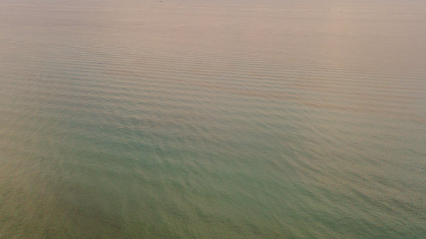 2022年6月25日，佛罗里达州棕榈滩金色多云清晨日出期间，蓝绿色和紫色的海浪涟漪的无人机视图图片下载