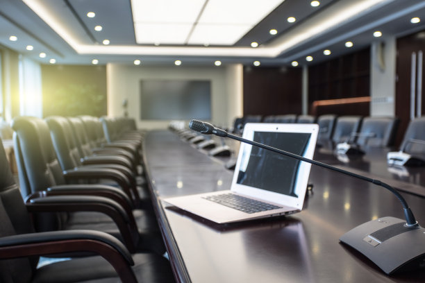 在会议室前面的麦克风和电脑的孤立视图，在背景中模糊的其他麦克风图片下载