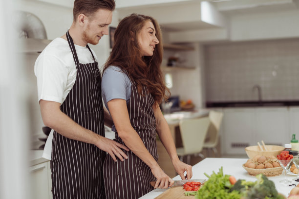 幸福的夫妻喜欢一起在厨房做饭。年轻的爱的男人和女人笑着在家里做健康的食物。图片下载