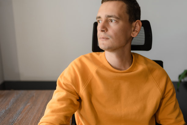 一位穿着黄色毛衣的有魅力的年轻人正看着窗外图片下载