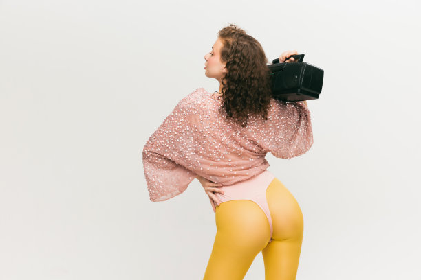 特写镜头。年轻时尚的女孩在前卫风格的服装在白色背景的背影。生动的风格，美丽，酷儿，怪胎，时尚概念。图片下载