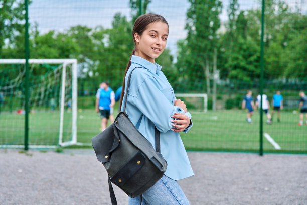 少女女学生的肖像看着相机，学校体育场的背景图片下载