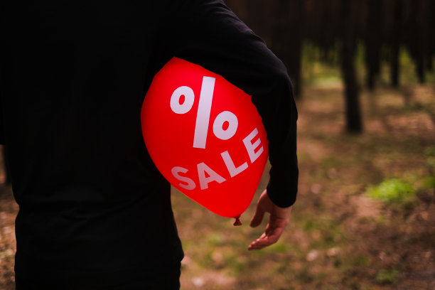 一个人拿着一个红色的气球，上面写着“折扣”图片下载