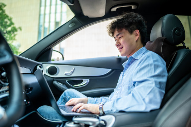 亚洲年轻英俊男子在车里使用笔记本电脑图片下载
