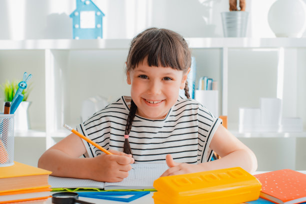 聪明集中的小7岁白人女孩孩子坐在书桌家学习远方做作业用教科书。图片下载