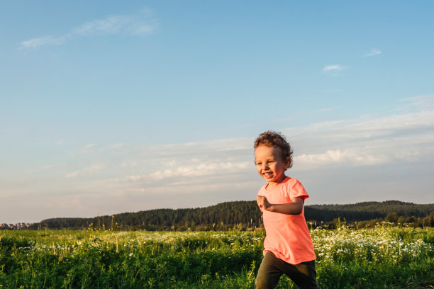 小男孩在草地上奔跑，夕阳西下。图片下载