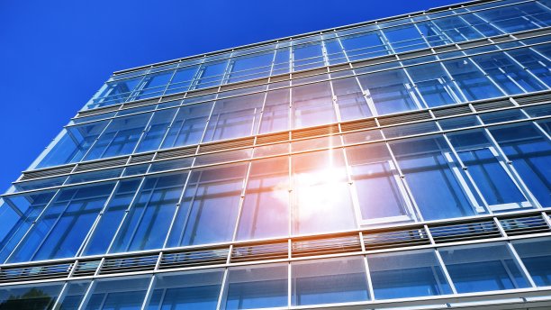 清澈的天空背景下的玻璃幕墙的现代办公大楼。图片下载