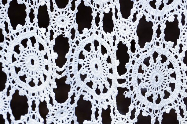 钩针白色花边在黑暗的背景，工艺，手工。花边的背景图片下载