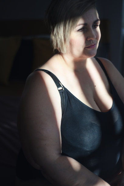 沮丧孤独的胖女人穿着内衣在家里低头思考。图片下载