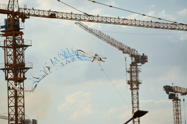 塑料和柳条木制风筝，背景是起重机的新建筑工地图片下载