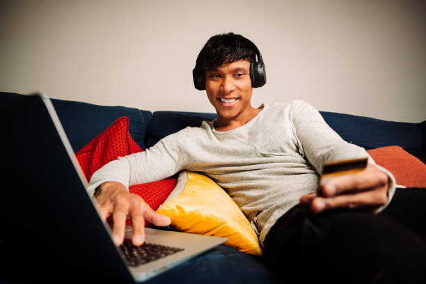 亚洲人在笔记本电脑上工作，用信用卡支付和听音乐图片下载