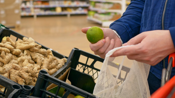 一名男子在一家商店购买青柠和生姜，用于治疗感冒和传染病。在当地市场购买新鲜的水果和蔬菜。商店货架上有精选的酸橙和苦艾根。图片下载