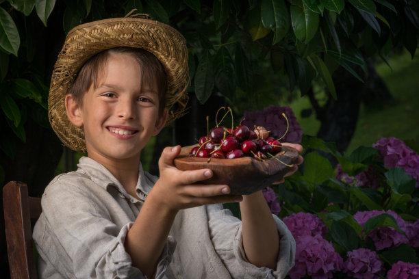 微笑快乐的孩子穿着简单的乡村服装，端着刚摘的樱桃去看望奶奶。图片下载