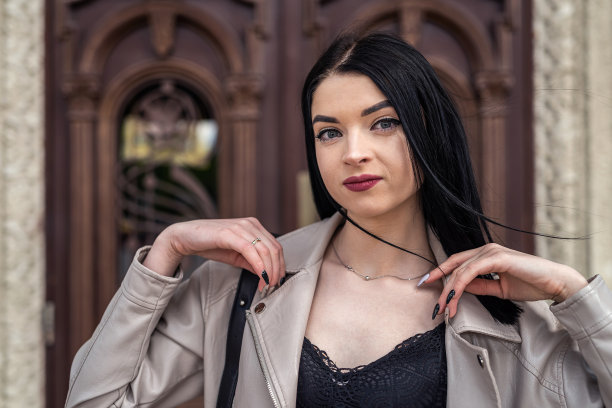 时髦漂亮的年轻女子的肖像在房子的老门外面摆姿势图片下载