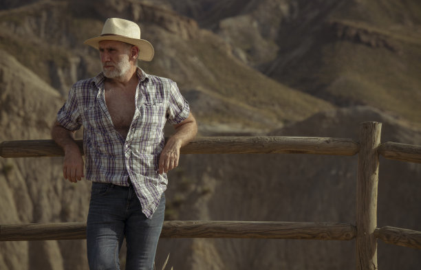 沙漠中戴太阳帽、穿着衬衫的成年男子肖像图片下载