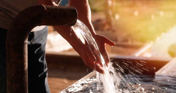 一名男子用从户外水管里流出的自来水洗手图片下载